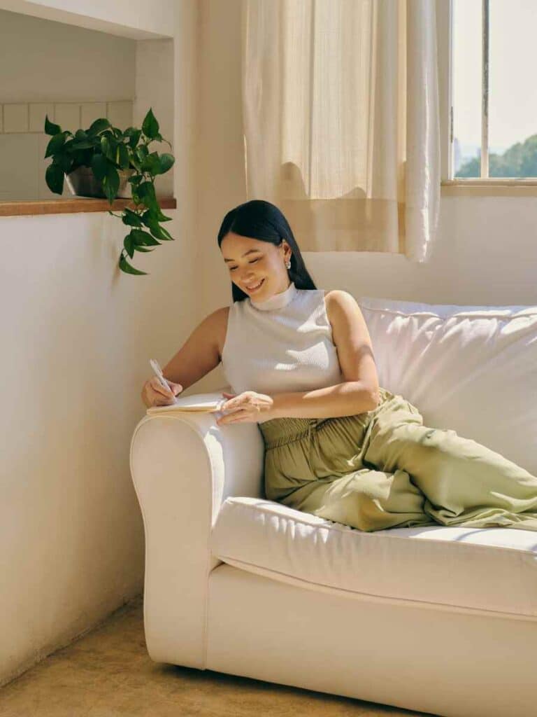 Woman sitting on sofa journaling.