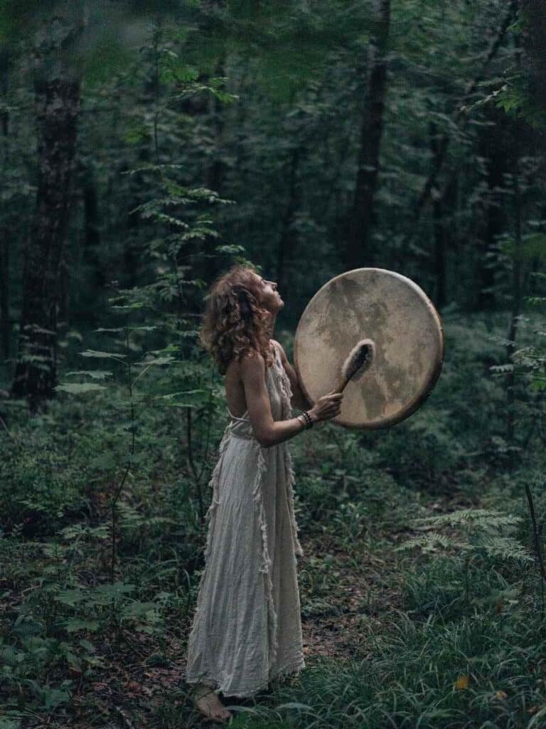 A woman holding a pagan tradition instrument. She's in nature.